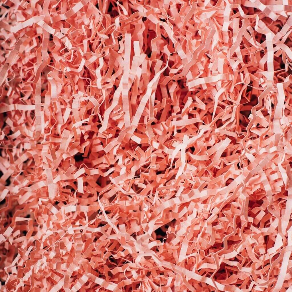 Eine Nahaufnahme von zerknittertem, zerrissenem rosa Papier, das den gesamten Rahmen ausfüllt und ein strukturiertes und mehrschichtiges Erscheinungsbild erzeugt.