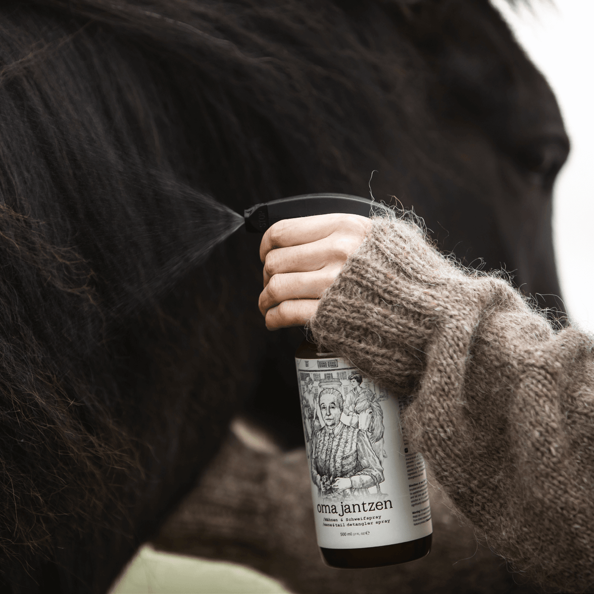 Wir sehen das Hestakofi Oma Jantzen Mähnen- und Schweifspray in Benutzung. Eine Frauenhand hält die Flasche in der Hand und sprüht das Produkt auf die Mähne.