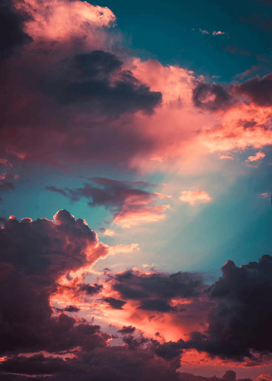 Dramatischer Sonnenuntergangshimmel mit leuchtend rosafarbenen, orangefarbenen und violetten Wolken, die vom Sonnenlicht angestrahlt werden und einen starken Kontrast zum tiefblauen Hintergrund bilden.